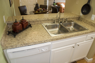 After: Remodeling features attractive two-level granite-style countertop with complementary refinished, refaced and repainted  white cabinets and doors with brushed nickel hardware.