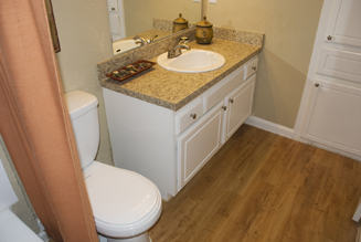 Very attractively remodled bathroom cabinet and sink featuring granite-style laminate countertop and back splash on a refaced cabinet repainted with a high gloss white enamel finish.