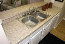 Remodeled double-sink granite laminate with pass-through bar countertops and white refaced raised-panel cabinetry increase tenat marketing appeal, property value and investment return for owners.