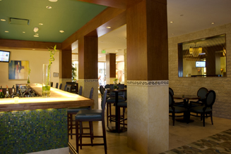 Custom built hotel Bar features wood framework, bar surface of translucent glass, and mosaic tile decorative facing.