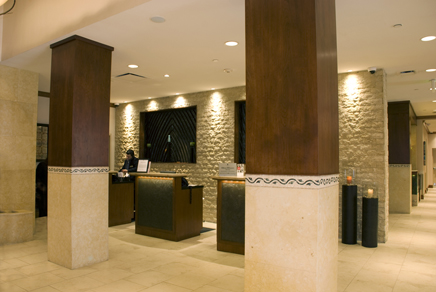 Hotel registration desks feature custom fine-wood construction with inlaid tile accent facing and granite counter and desktops.
