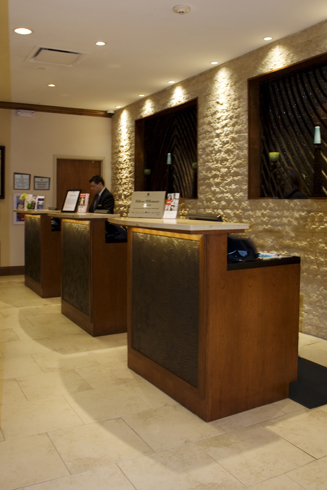 Registration desks for the hotel feature separate island modules, custom fine-wood construction with inlaid tile accent facing and granite counter and desktops.