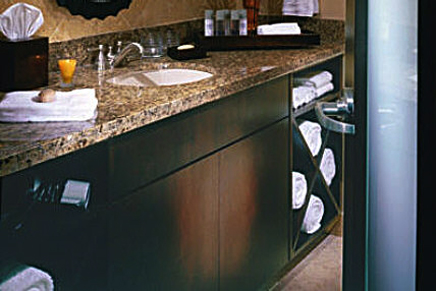 Bonier custom cabinetry and granite countertops for hotel guest bathrooms features cabinet reconstruction and refinishing with custom built-in towel holding compartments.