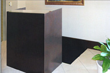 Small relocatable registration cabinet-style desk, custom built with dark wood-stained finish and granite countertop.