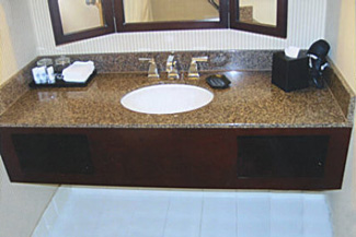 Custom walnut stained guest room vanities with granite countertop, and specially crafted picture framed mirrors.
